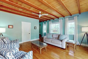 A living room with a wooden ceiling, a white ceiling fan, a beige sofa, a patterned blue sofa, a glass coffee table, and a lamp on a side table. - Villa Sunset - Private Pool (West Palm Beach)