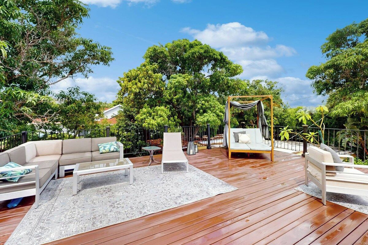 An outdoor deck with a sofa, chairs, and a swing set.