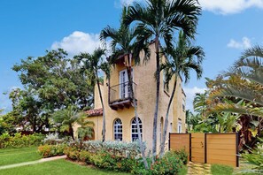 A two-story building with a balcony, surrounded by lush greenery and palm trees. - Villa Sunset - Private Pool (West Palm Beach)