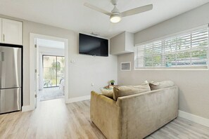 A modern kitchen with a built-in refrigerator, a ceiling fan, and a flat-screen TV mounted on the wall. - The Palms Unit 2 - Enclosed Yard (Fort Lauderdale)