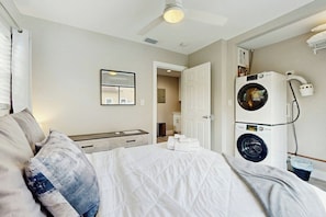 A hotel room with a bed, a ceiling fan, a washing machine, and a mirror. - The Palms Unit 2 - Enclosed Yard (Fort Lauderdale)