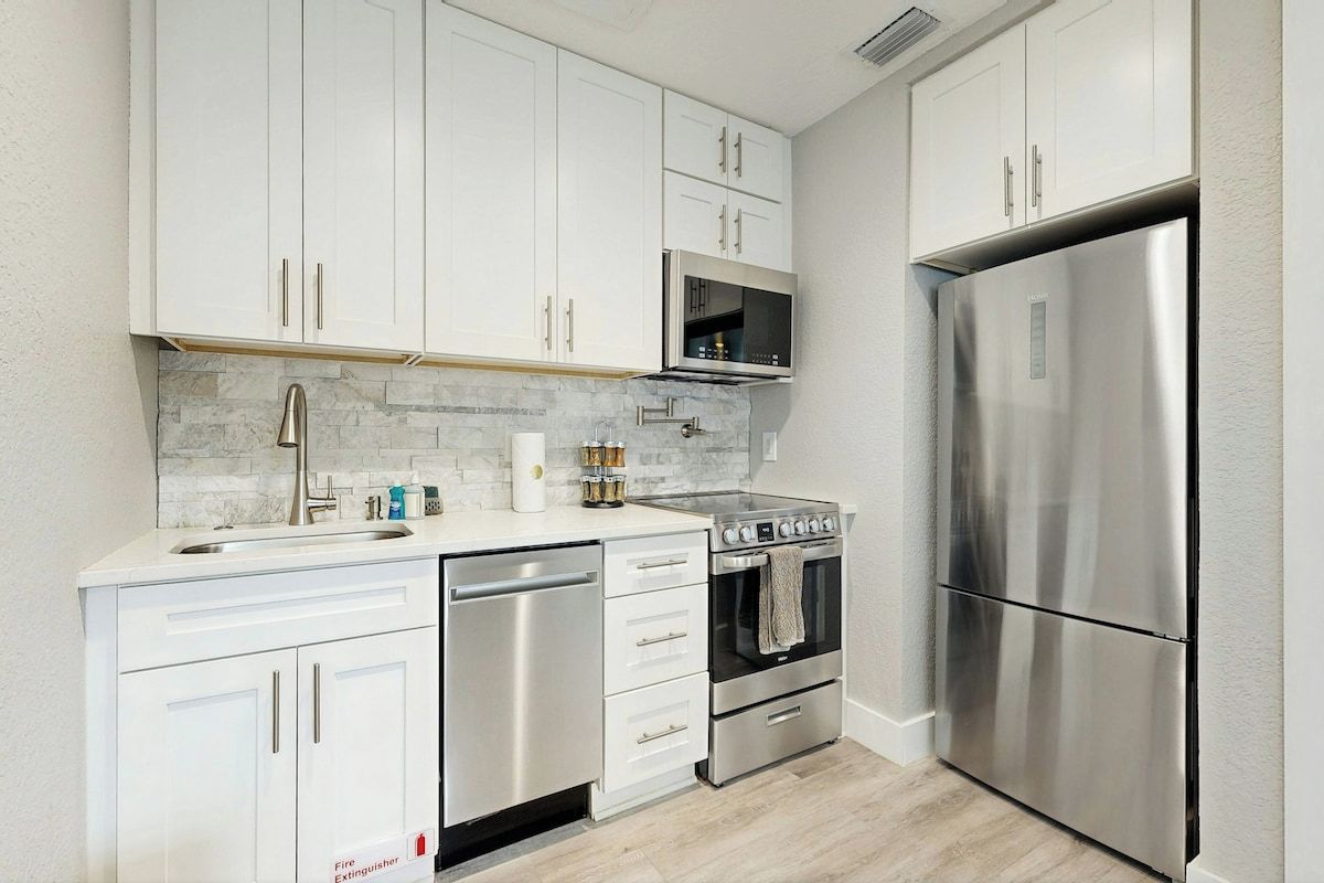 A kitchen with white cabinets, stainless steel appliances, a microwave, a refrigerator, and a dishwasher.