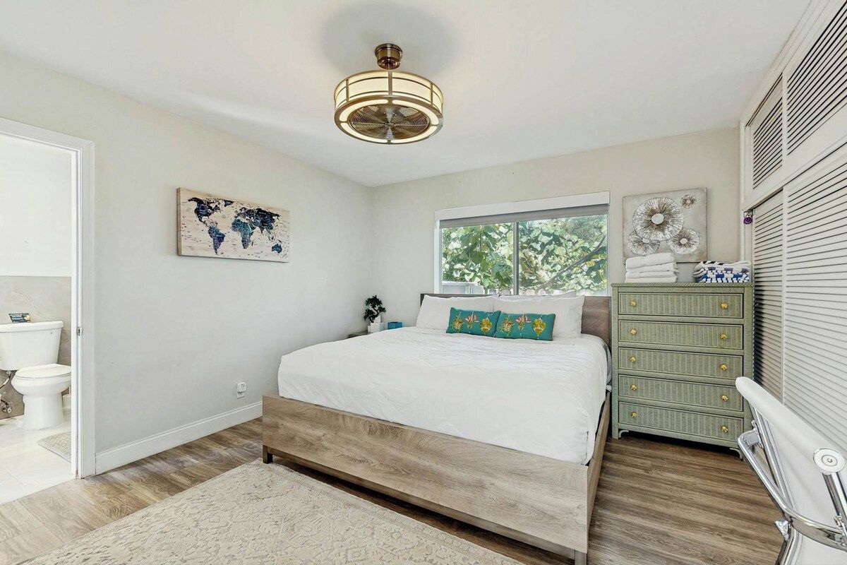 A bedroom with a bed, a dresser, a window, and a ceiling fan.
