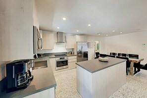 A modern kitchen with stainless steel appliances, a central island, and a seating area with a table and chairs. - Designer Delight - Private Pool (Wilton Manors)