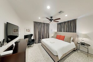 A hotel room with a bed, a desk, a chair, a TV, curtains, a ceiling fan, and a small table. - Designer Delight - Private Pool (Wilton Manors)