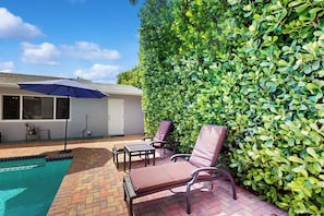 A swimming pool area with a patio, lounge chairs, and a hedge. - The Front House - Private Pool (Fort Lauderdale)