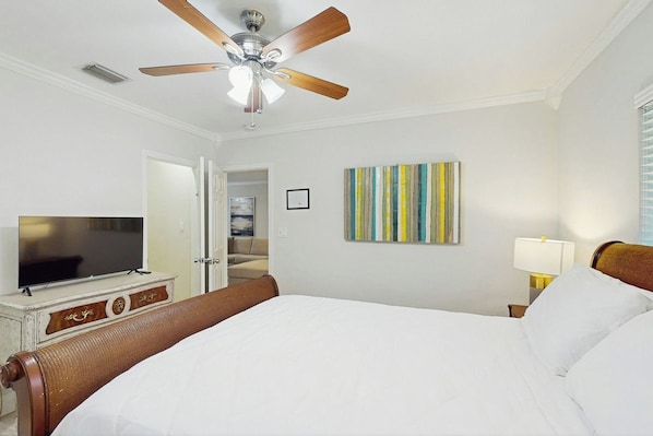 A hotel room with a bed, a ceiling fan, a television, a painting, and a nightstand with a lamp. - The Front House - Private Pool (Fort Lauderdale)