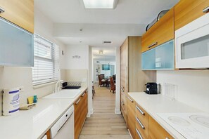 A narrow kitchen with wooden cabinets, a microwave, and a sink. - Miami Lux Haven - Near Beach (Miami Beach)