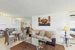 A modern living room with a glass coffee table, beige sofa, and wicker chairs. - Miami Lux Haven - Near Beach (Miami Beach)