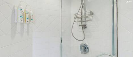 Una ducha moderna con cabina acristalada, cabezal de ducha manual y toallero de vidrio.