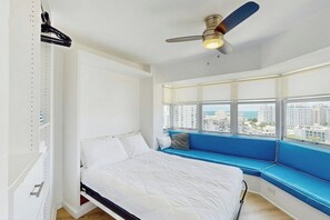 A bedroom with a bed, a window seat, a ceiling fan, and a view of the city. - Miami Lux Haven - Near Beach (Miami Beach)