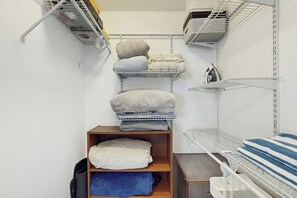 Um espaço de armazenamento com prateleiras cheias de toalhas dobradas e uma cesta de roupa.