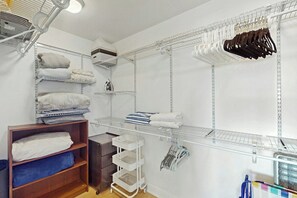 A well-organized closet with shelves, hanging space, and a wooden shelf unit. - Miami Lux Haven - Near Beach (Miami Beach)