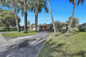 A residential street with houses, palm trees, and a clear sky. - Tropical Bliss Alfresco Villa (Pompano Beach)