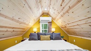 A room with a sloped ceiling, a bed with pillows, two bedside lamps, and a window with curtains. - Newly built private cabin with fire pit, Sauna. Close to National park entrance (Fort Valley)