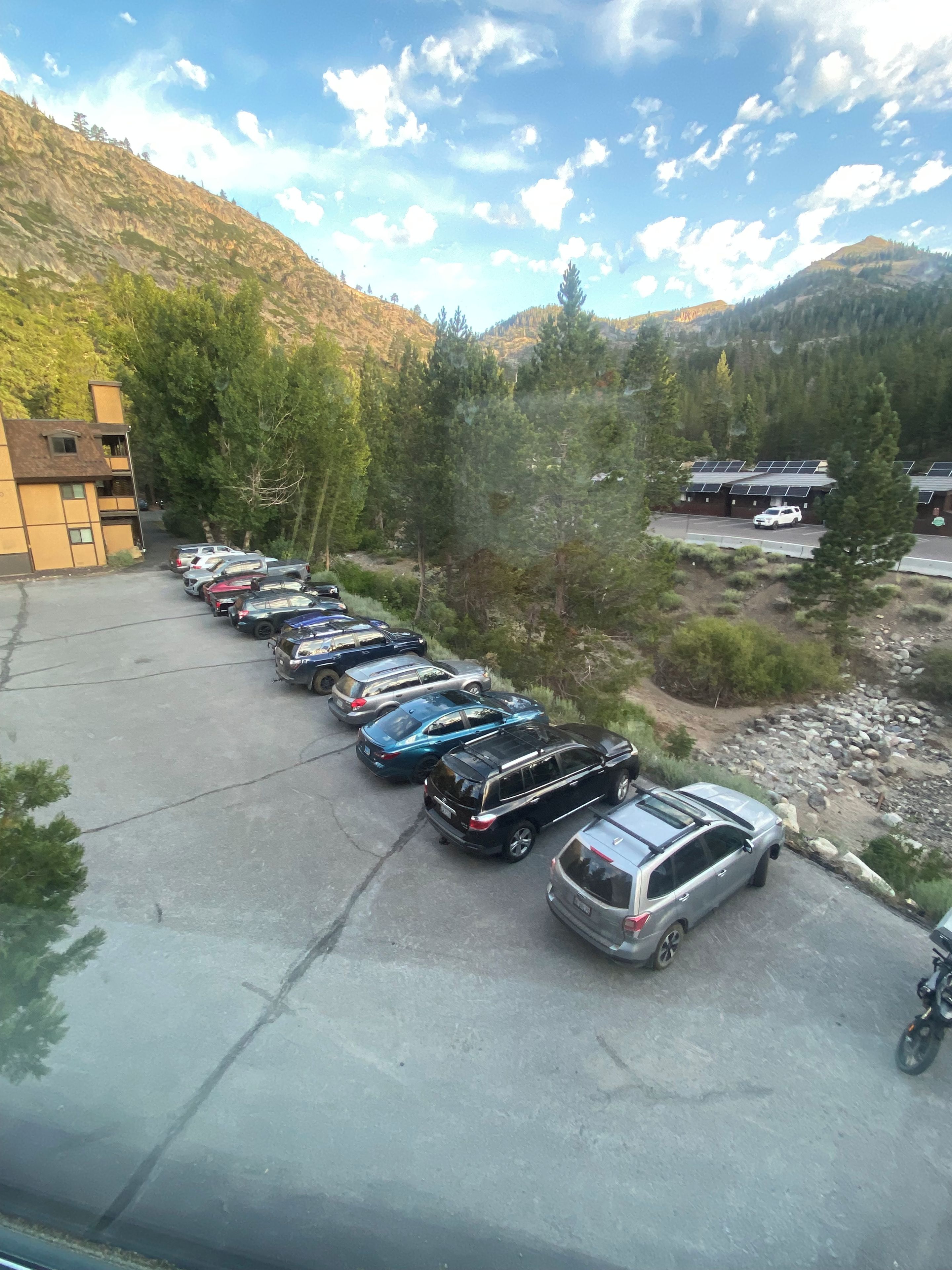 A parking lot with multiple cars and a building with a sloped roof.