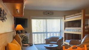 Ein gemütliches Wohnzimmer mit einer Couch, einem Holztisch und einem Etagenbett.