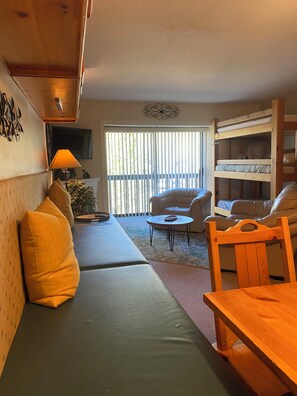 Una sala acogedora con un sofá, una mesa de madera y una cama litera.