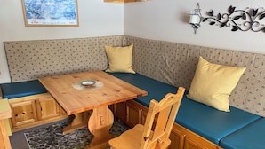Eine gemütliche Ecke mit einem Holztisch, einer Bank und einem gemusterten Teppich.