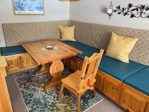 Un rincón acogedor con una mesa de madera, un banco y una alfombra estampada.