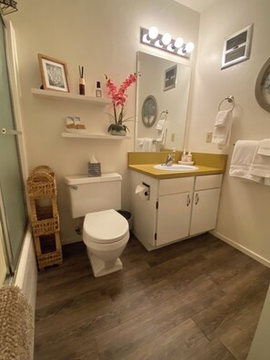 Un baño con inodoro, lavamanos, espejo y tocador.
