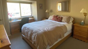 Ein Schlafzimmer mit einem Bett, Nachttischen, einem Schreibtisch und einem Fenster.