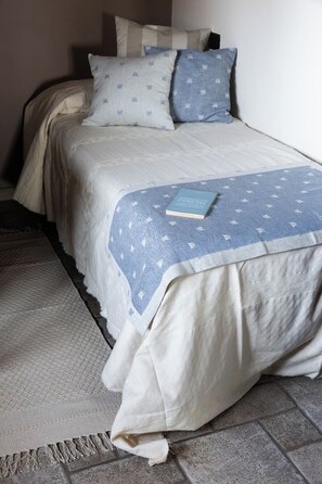 A bed with a blue and white patterned bedspread, a book on the bed, and a grey patterned rug beside it. - Gelsomina Country House - A historic farmhouse nestled in the peaceful Umbrian countryside (Umbria)