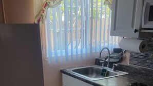 Una cocina compacta con refrigerador, pileta y microondas.