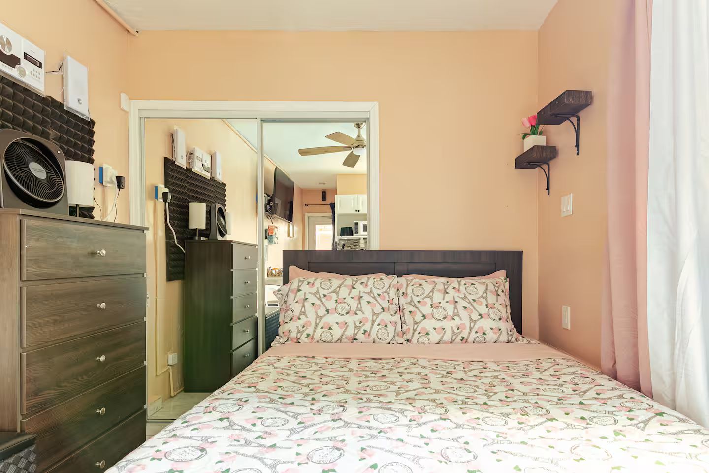 Un dormitorio con cama, cómoda y ventilador de techo.