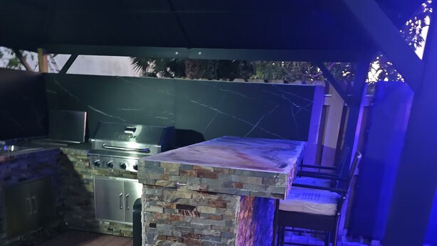 Un área de bar al aire libre con mostrador de piedra y asientos.