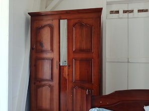 Une armoire en bois avec un miroir et un lit avec une tête de lit en bois.