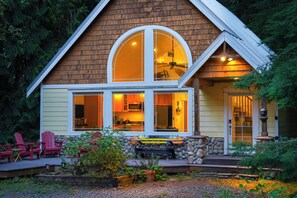 A two-story house with a large bay window, a stone fireplace, and a deck with Adirondack chairs. - Mt Baker Snowline Chalet | Private Hot Tub + Fireplace | Sleeps 6 (Deming)