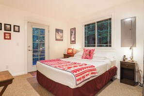 A bedroom with a large bed, a window with a view of trees, a bedside table with a lamp, and framed pictures on the wall. - Mt Baker Snowline Chalet | Private Hot Tub + Fireplace | Sleeps 6 (Deming)