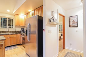 A kitchen with wooden cabinets, a stainless steel refrigerator, and a built-in oven.