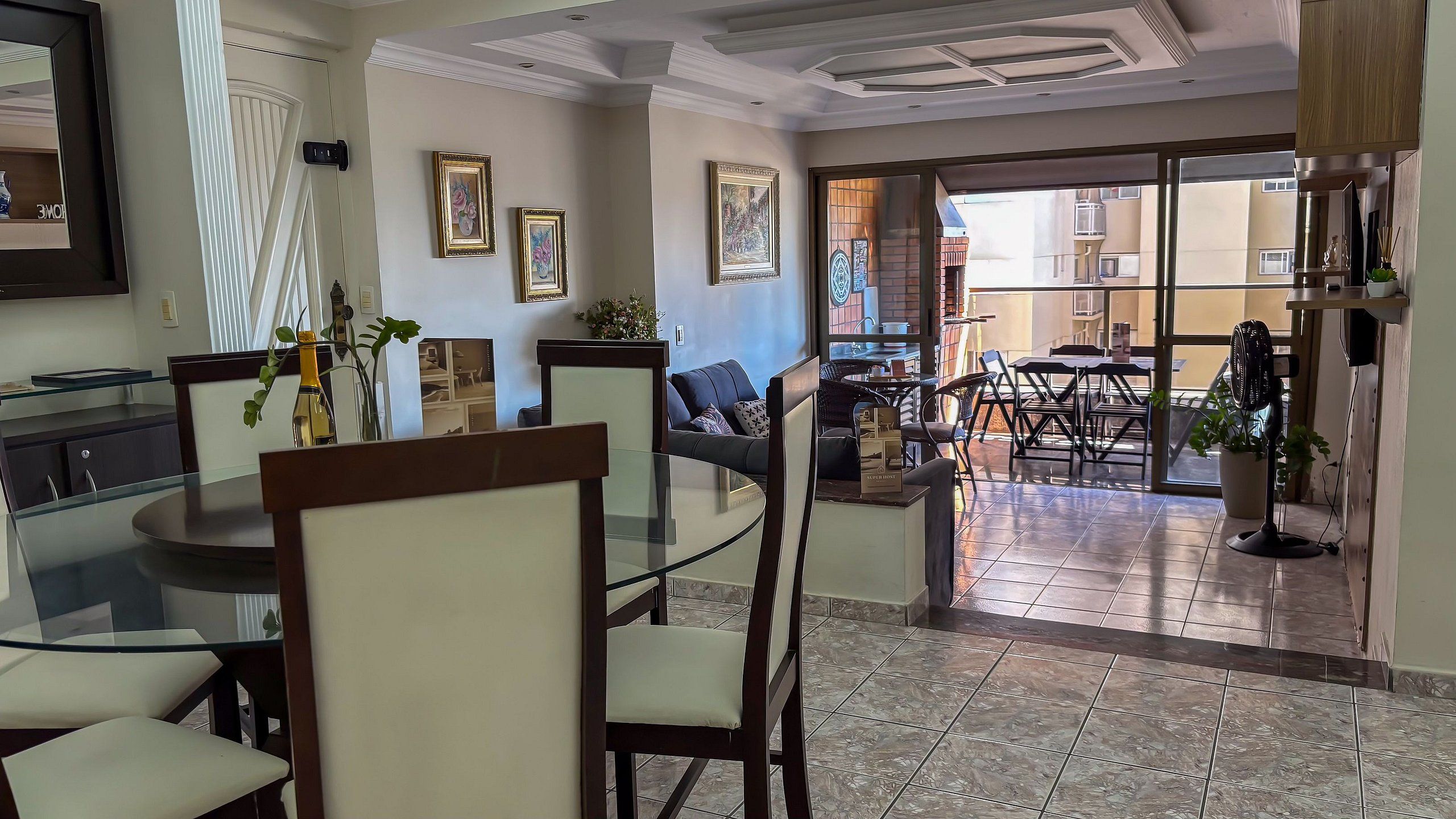 Un comedor con una mesa de vidrio, sillas y vista del patio exterior.