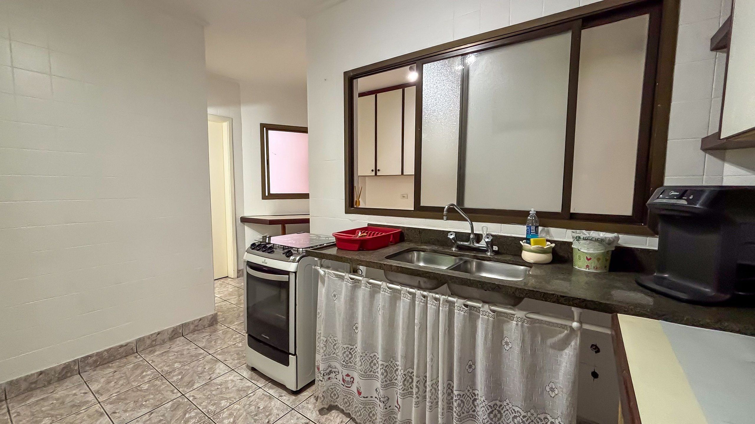 Una cocina compacta con estufa, horno, lavamanos y un espejo grande sobre la encimera.