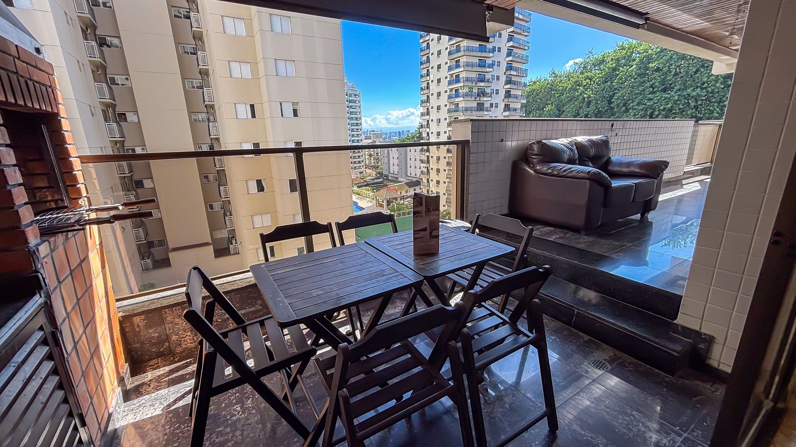 Un balcon avec une table et des chaises, un canapé et une vue sur les immeubles de grande hauteur.