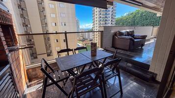 Un balcon avec une table et des chaises, un canapé et une vue sur les immeubles de grande hauteur.