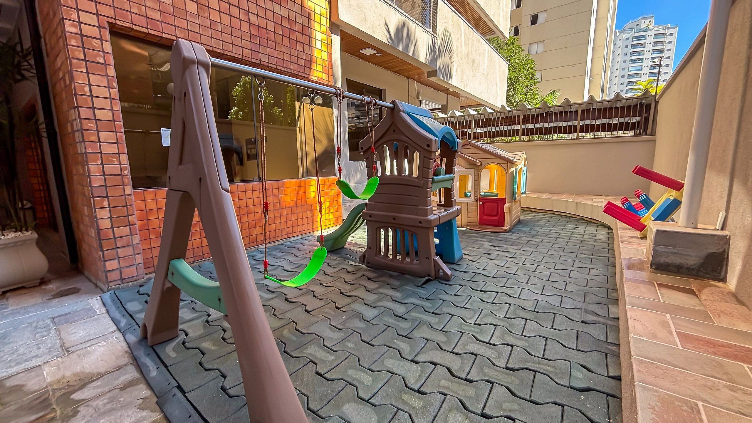 A children's play area with a slide, swings, and a small building structure.