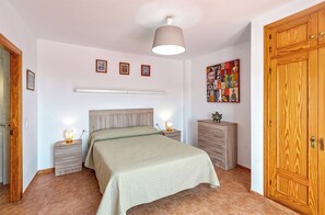 A bedroom with a bed, bedside tables, a dresser, a ceiling light, and a wall-mounted artwork. - Vistamar Duplex, with spacious terraces and ocean views in Frigiliana (Frigiliana)