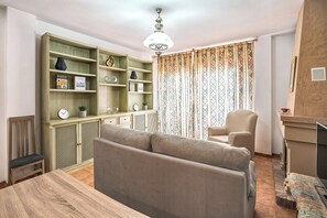 A living room with a sofa, a wooden dining table, a bookshelf, and a patterned curtain. - Vistamar Duplex, with spacious terraces and ocean views in Frigiliana (Frigiliana)