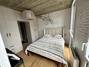 A bedroom with a bed, wardrobe, and a hanging light fixture. - Cozy, fully equipped one-bedroom apartment in the city center (Brest)