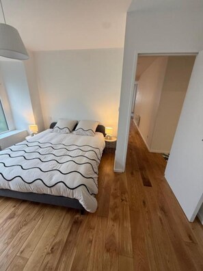 A bedroom with a bed, bedside lamps, and a wooden floor. - Cozy, fully equipped one-bedroom apartment in the city center (Brest)
