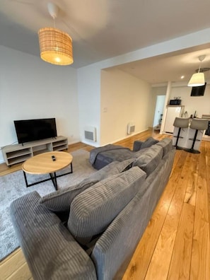 A modern living room with a sectional sofa, a round coffee table, a flat-screen TV, and a dining area with chairs and a table. - Cozy, fully equipped one-bedroom apartment in the city center (Brest)