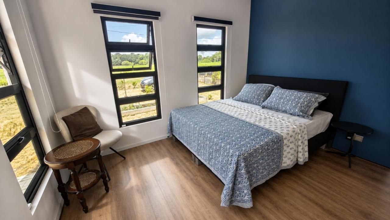 Een slaapkamer met een bed, een stoel en twee ramen.
