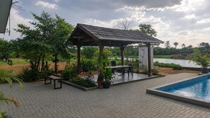 A covered outdoor area with a pool, seating, and potted plants. - Guesthouse AngaLampoe (Lelydorp)
