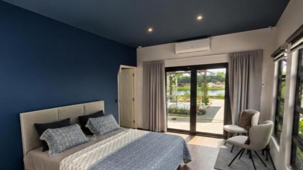 A bedroom with a bed, a chair, and a view of an outdoor area. - Guesthouse AngaLampoe (Lelydorp)