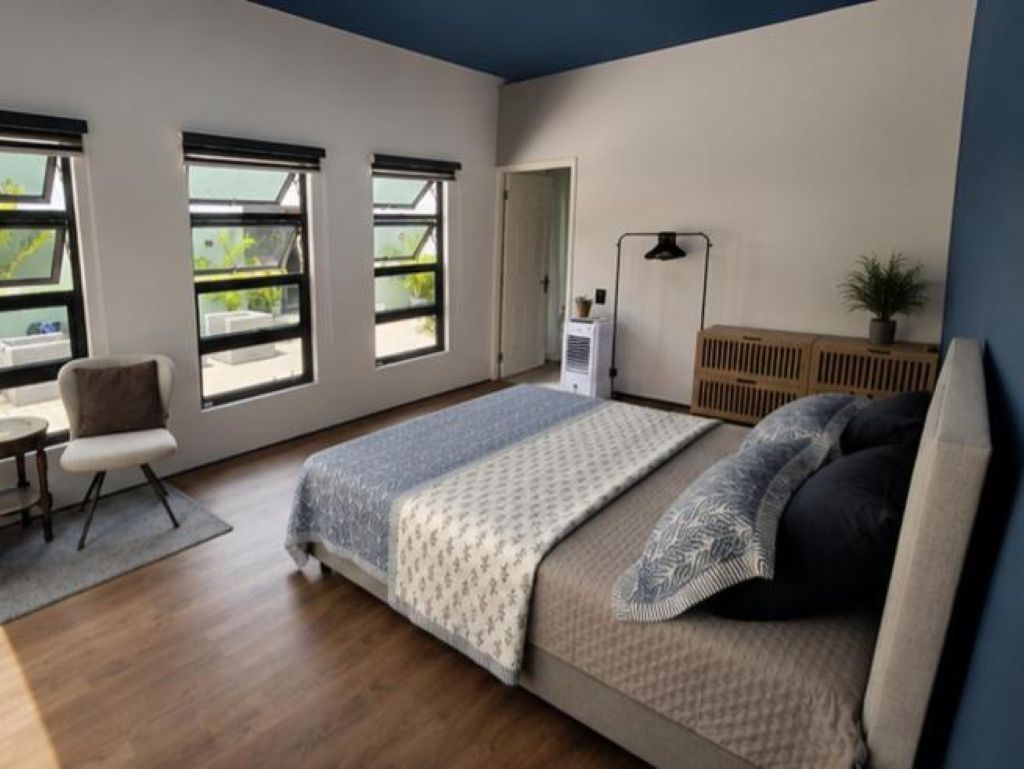A bedroom with a bed, a desk, a chair, a radiator, and a window.
