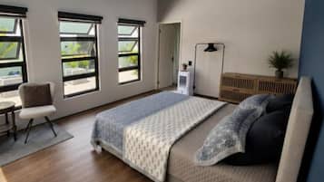 A bedroom with a bed, a desk, a chair, a radiator, and a window.