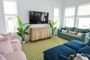 A living room with a checkered floor, a green sofa, a blue sofa, and two potted plants. - Most Kid-Friendly 30A Home + Private Heated Pool + Golf Cart + All Beach Gear (Inlet Beach)